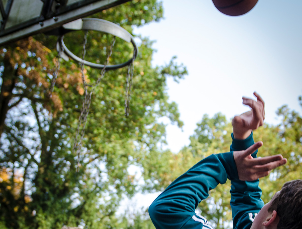 Ein Junge wirft einen Ball in einen Basketballkorb
