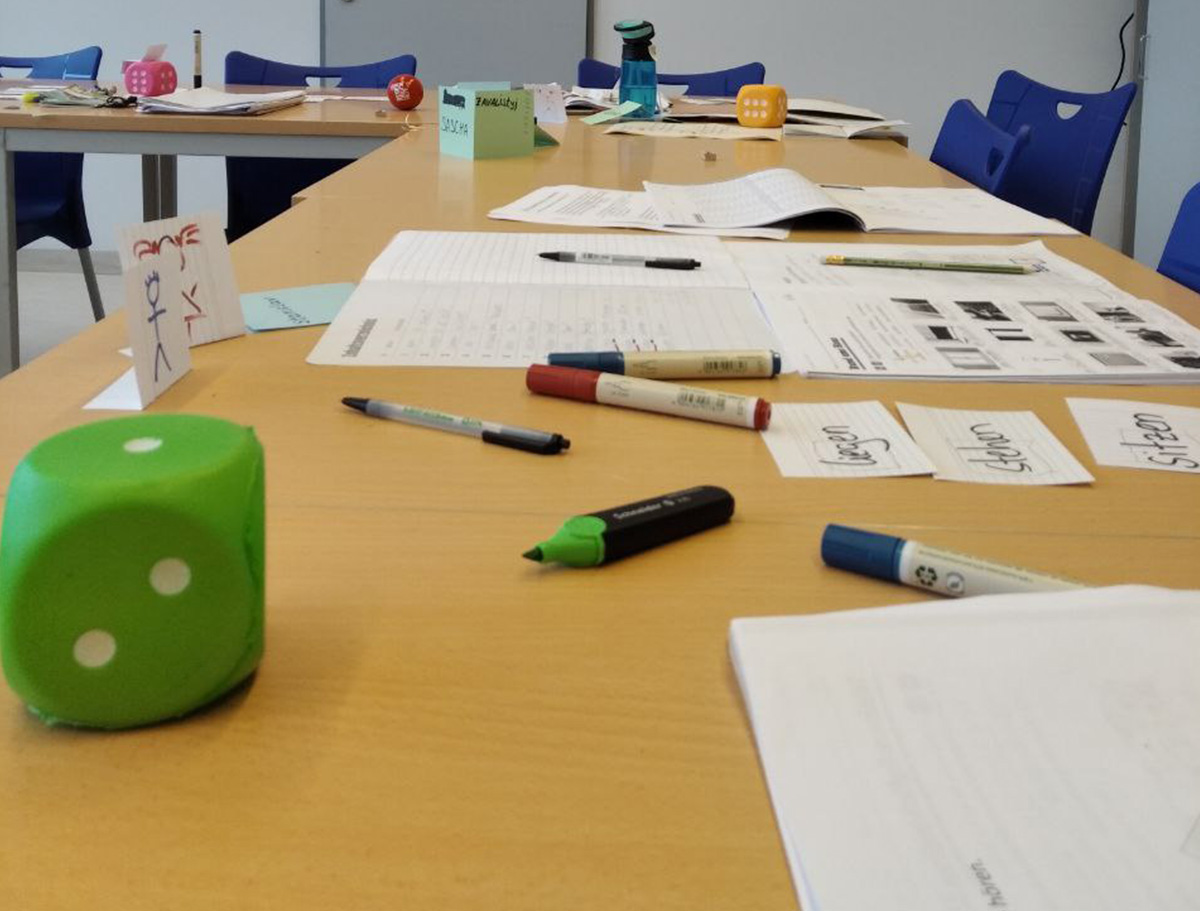 Verschiedene Zettel und ein grüner Würfel auf einem Tisch