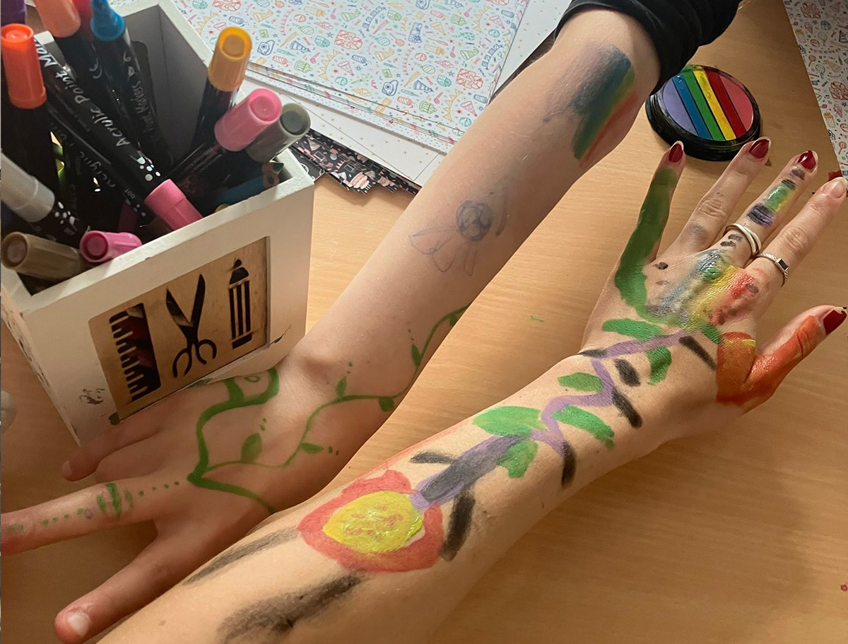 zwei bunt bemalte Kinderarme strecken sich einander entgegen